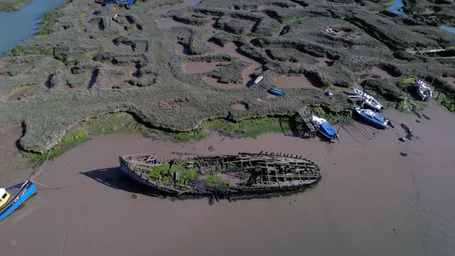Shipwreck Covered With Moss Near Salt Marshes In Tollesbury Marina, Essex, United Kingdom. Aerial Tilt-down