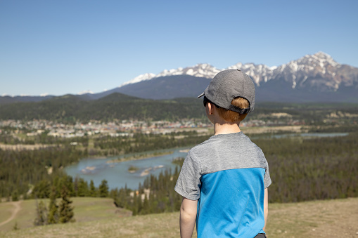 Happy Young Hiker Boy at the Old Fort Point Hiking Trail, Jasper, Alberta, Canada on a nice day of summer. The Canadian Rockies are in the background.