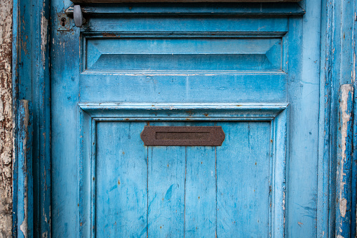 A vertical shot of a brown wooden single door of an abandoned building. The inner structure of the door is visible on the right.