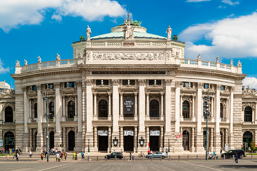 Vienna, Austria - June 2, 2022: The Burgtheater in downtown Vienna, Austria with people walking by on a sunny day.