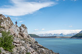 Man stands on top of rock above lake