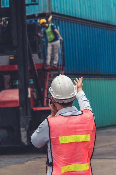 istock Industrial worker works with co-worker at overseas shipping container yard . Logistics supply chain management and international goods export concept . 1464322654