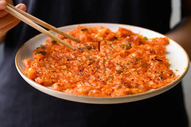 Kimchi pancake (Kimchi jeon or kimchi buchimgae) with hand ready to eating, Korean food