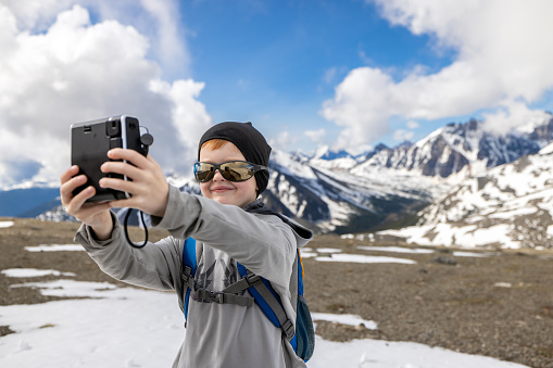 Young Redhead Boy Taking Instant Picture at the top of Whistlers Mountain, Alberta, Canada on a nice day of summer.