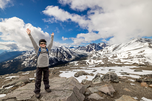 Young Boy With Arms Raised at  the top of Whistlers Mountain, Alberta, Canada on a nice day of summer.