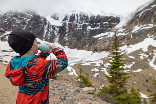 Young Boy Drinking Water at Mount Edith Cavell, Jasper, Canada. He is using a reusable water bottle.