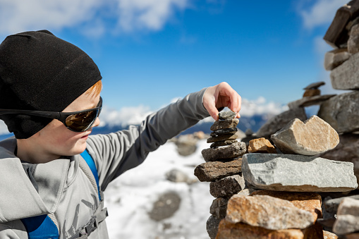 Young Redhead Boy Rock Stacking at the top of Whistlers Mountain, Alberta, Canada