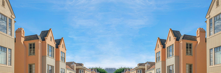 Abstract mirrored background Neighborhood residential buildings on a low angle view at San Francisco, California. There are townhouses and single family house in a row against the sky