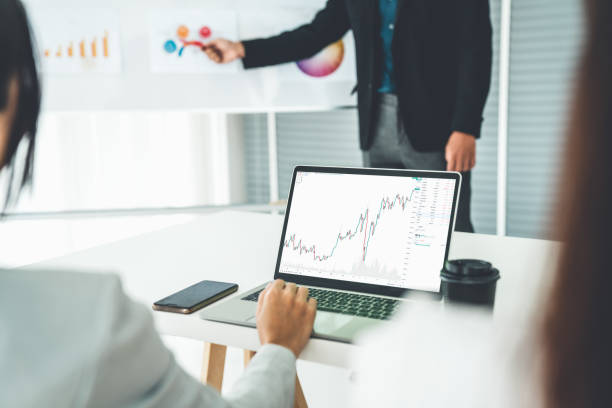 istock Businesswoman in analyze stock market data using laptop computer proficiently at the office while attending a group meeting with business team . 1464329650