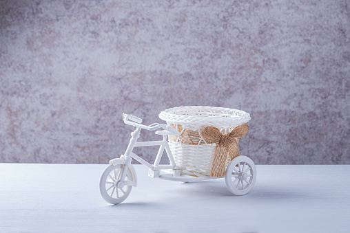 A flower pot or candy box on the trunk of a toy white bike. Copy space.