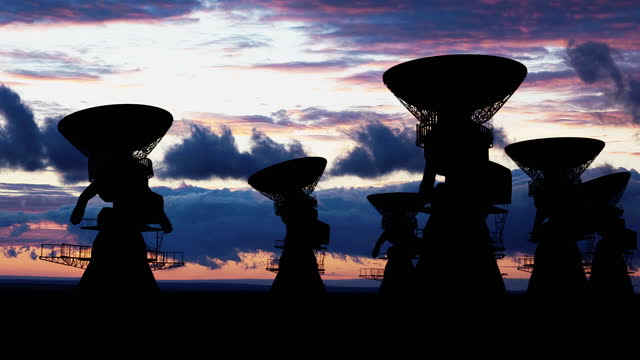 Big satellite dishes against the colored sunset sky with clouds