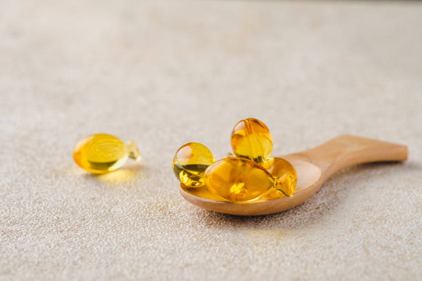 木のスプーンにタラ肝油の接写、栄養補助食品のコンセプト。 - fish oil vitamin pill cod liver oil nutritional supplement ストックフォトと画像