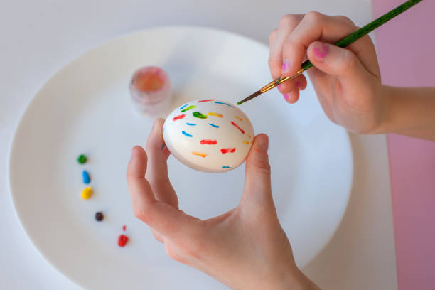 istock A ten-year-old girl decorates an egg for Easter. Close-up. 1464343480