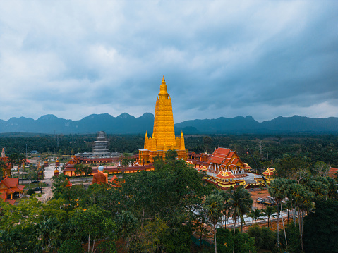 Scenic aerial view of buddhist temple and golden stupa surrounded by the jungles in Thailand