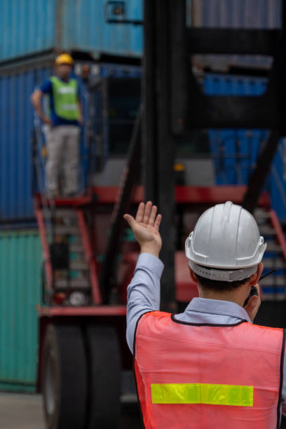 istock Industrial worker works with co-worker at overseas shipping container yard . Logistics supply chain management and international goods export concept . 1464348732