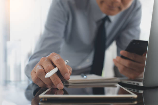 istock Asian businessman working on digital tablet and laptop computer at office 1464349426