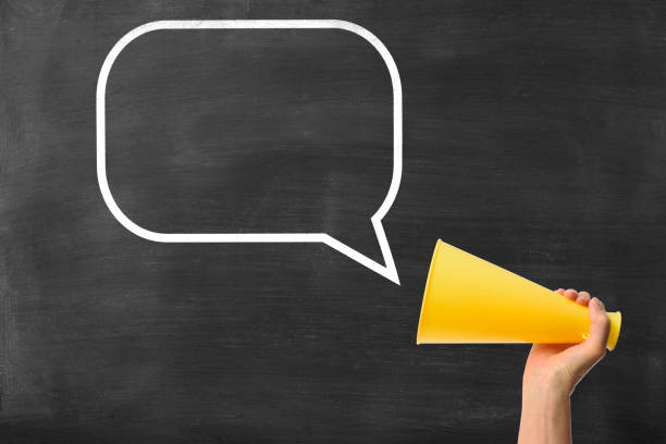 istock Hand holding megaphone with blank speech bubble on blackboard 1464357467