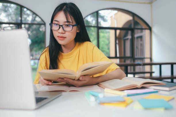 junge asiatische studentin bereitet sich darauf vor, ein buch für prüfungen an der universität zu lesen. - reading and writing exam preparation education stock-fotos und bilder