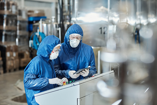 Portrait of two workers wearing protective gear operating equipment at industrial factory