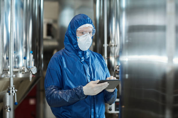 istock Worker wearing protective gear and mask using tablet at industrial factory 1464359768