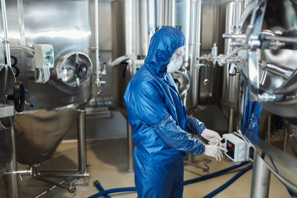 istock Worker wearing protective suit pressing buttons on equipment in factory workshop 1464359954
