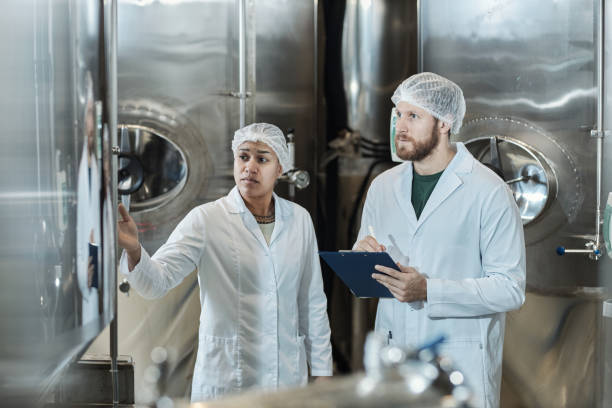 istock Two workers wearing lab coats in food factory workshop 1464360203
