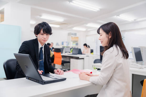 un membre du personnel masculin au comptoir - laptop japanese ethnicity businessman desk photos et images de collection