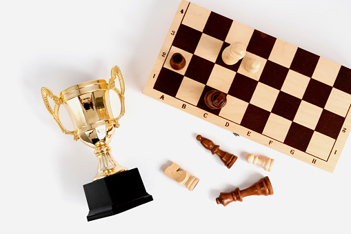 White queen among black pawns on wooden chess board against dark background