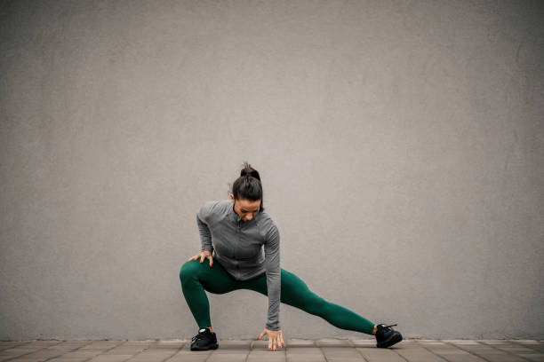 une sportive en forme se dégourdit les jambes et s’échauffe pour courir dans la rue. - échauffement photos et images de collection