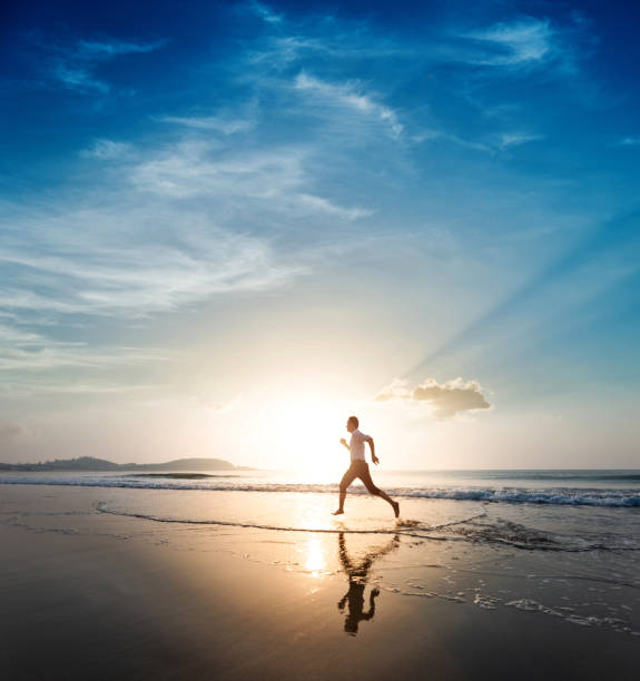 istock Man jogging on the beach at sunset 1464364732