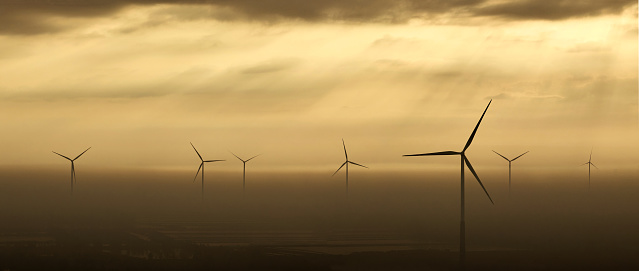 Aerial view of group of wind turbines on sunrise yellow sky.