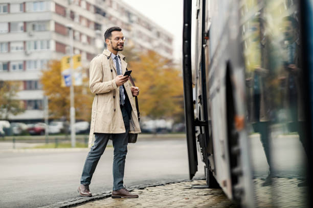 istock A businessman is using his phone and entering a bus downtown. 1464366717