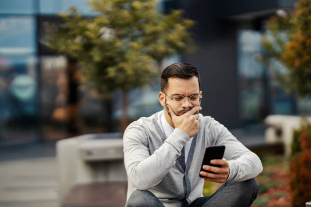 istock A serious businessman is sitting outdoors and thinking while looking at the phone. 1464367266