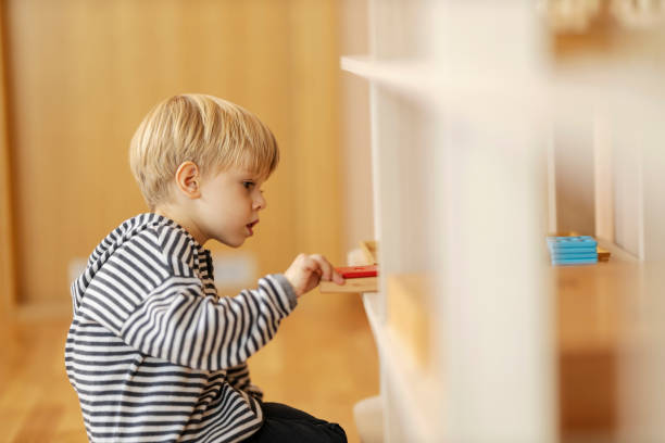 istock A boy is taking wooden educational toy form a shelf at kindergarten. 1464368606