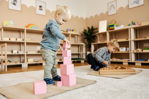 Children at kindergarten are playing games with wooden montessori toys and learning through the game.