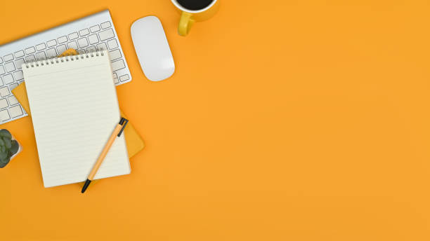istock Top view of notepad, keyboard, mouse and coffee cup on yellow background. Copy space for your text. 1464372595