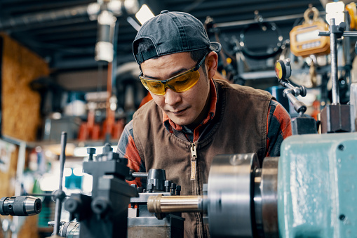 Mid adult man machining parts in a metal fabrication workshop in Japan