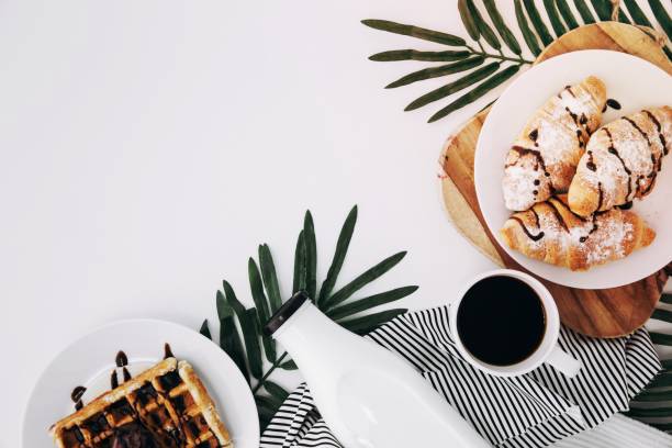 istock overhead view baked croissant waffles bottle coffee cup leaves white backdrop 1464375755