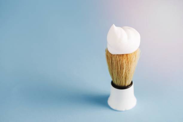 istock overhead view classic shaving brush with white foam against blue background 1464376917