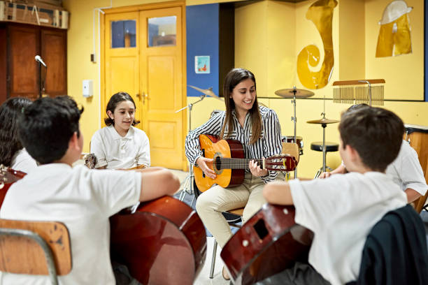 istock School children playing acoustic guitars with teacher 1464380279