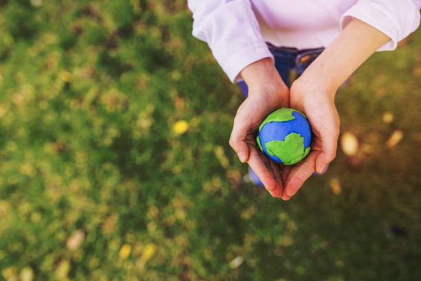 istock elevated view small clay globe cupped hands grass. High quality beautiful photo concept 1464383604