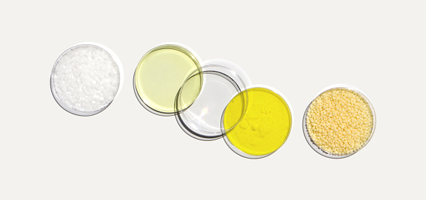 Microcrystalline wax, Poly Aluminium chloride liquid, Potassium Chromate and Candelilla wax in Petri dish on white laboratory table. Chemical ingredient for Cosmetic and Toiletries product. Top View