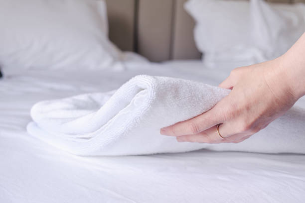 istock woman's hand puts a clean white terry towel on the bed 1464390224