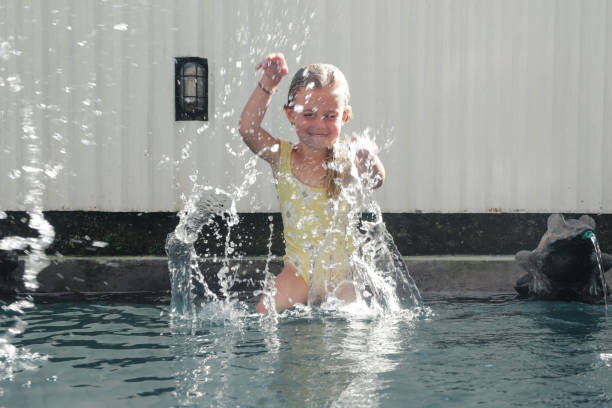 retrato de una adorable niña de 5 años sentada al borde de la piscina y salpicando agua con las manos - child 4 5 years laughing little girls fotografías e imágenes de stock