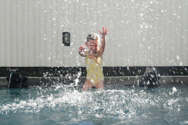 retrato de una adorable niña de 5 años sentada al borde de la piscina y salpicando agua con las manos - child 4 5 years laughing little girls fotografías e imágenes de stock