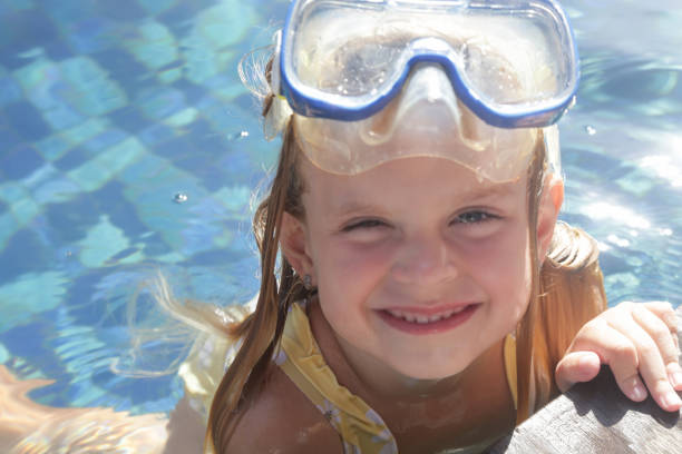 adorable niña alegre de 5 años con máscara de snorkel posando junto a la piscina - eyewear child glasses 6 7 years fotografías e imágenes de stock