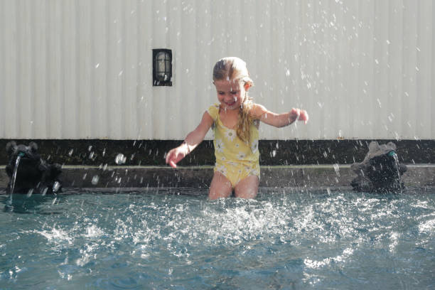 retrato de una adorable niña de 5 años sentada al borde de la piscina y salpicando agua con las manos - child 4 5 years laughing little girls fotografías e imágenes de stock