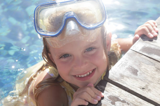 adorable niña alegre de 5 años con máscara de snorkel posando junto a la piscina - eyewear child glasses 6 7 years fotografías e imágenes de stock