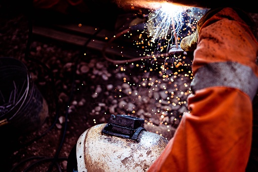A closeup of a worker welding the railroad