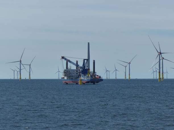 istock Cargo ship carrying load on the sea surrounded y wind turbines 1464399557